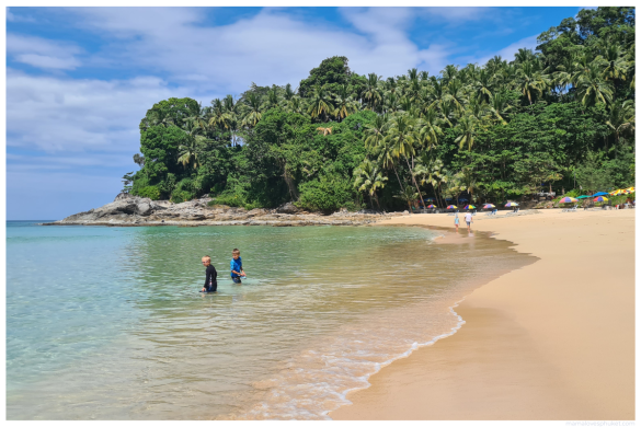 children playing in the calm dry season waters of surin beach, phuket